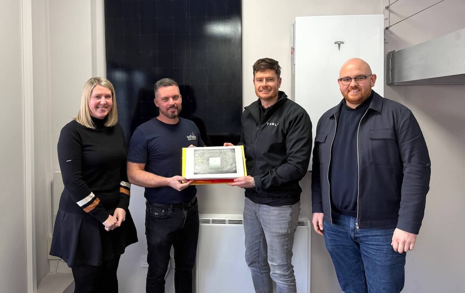 The Infinity Energy Services and Tesla Energy teams celebrating the 1,000th Tesla Powerwall installation milestone with a commemorative cake