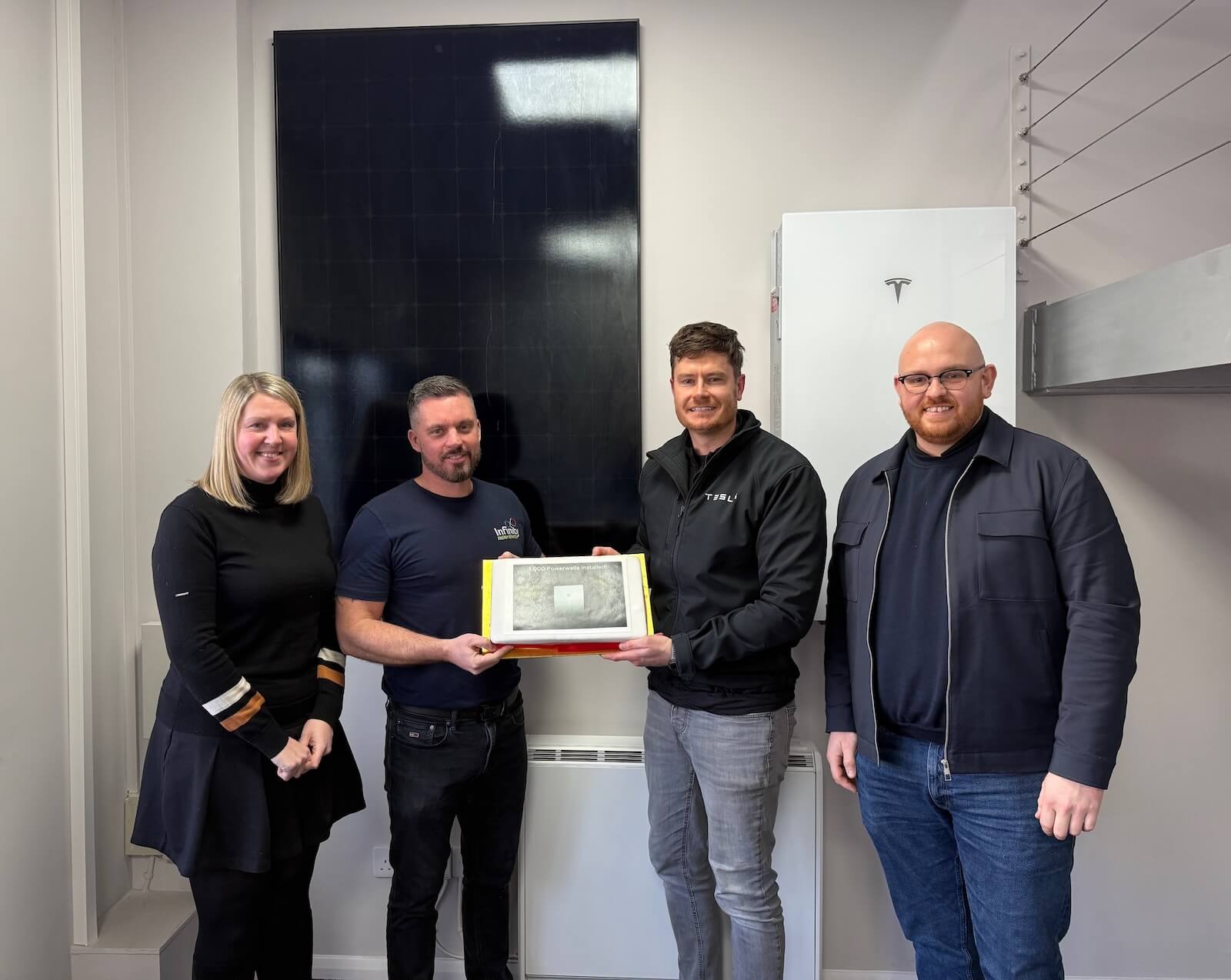 A photo showing Infinity Energy Services and Tesla Energy staff celebrating the milestone of having installed 1,000 Tesla Powerwall batteries.