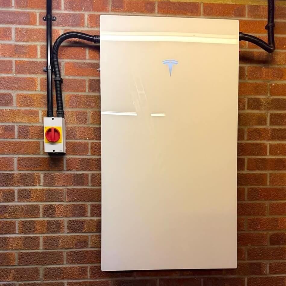 A Tesla Powerwall 3 battery unit professionally installed on a brick wall with an isolator switch, covered by a comprehensive 10-year warranty