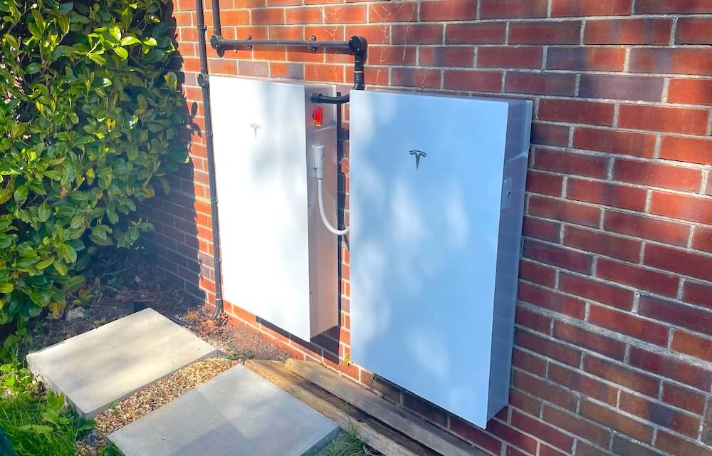 Two Tesla Powerwall 3 battery storage units installed on the exterior wall of a home in Woodley, Berkshire